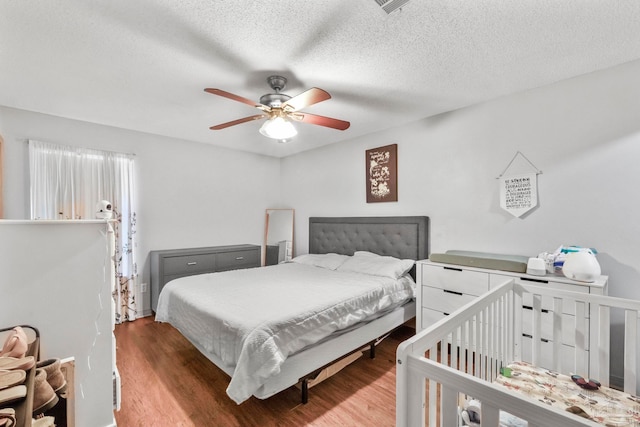 bedroom with a textured ceiling, hardwood / wood-style flooring, and ceiling fan