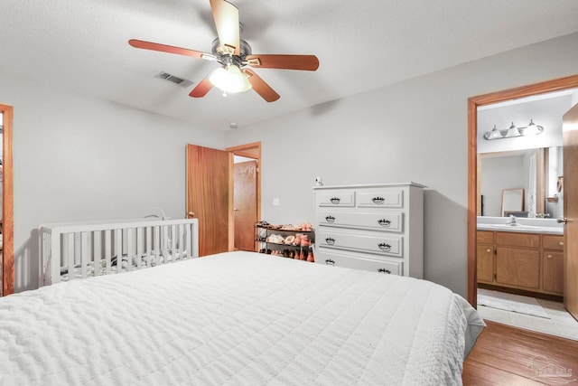 bedroom featuring connected bathroom, ceiling fan, light hardwood / wood-style flooring, and sink