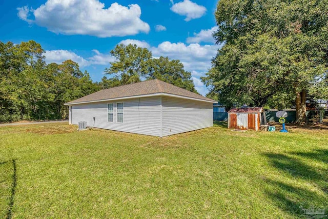 view of side of property featuring a yard, a shed, and central AC unit