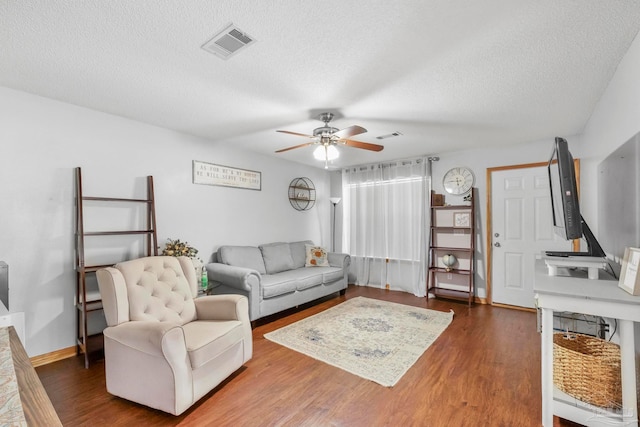 living room with a textured ceiling, ceiling fan, and dark hardwood / wood-style flooring