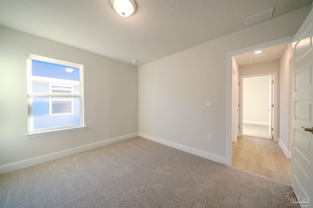 unfurnished room featuring light carpet and a textured ceiling