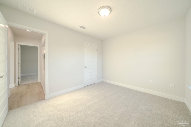 unfurnished bedroom with light colored carpet and a closet