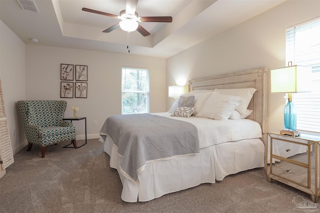 carpeted bedroom featuring ceiling fan and a tray ceiling