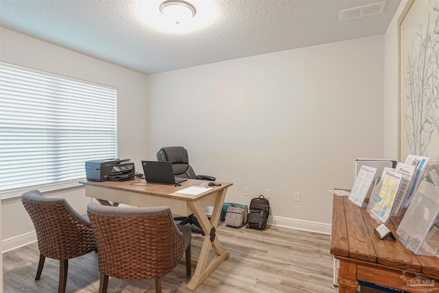 office with light hardwood / wood-style floors and a textured ceiling