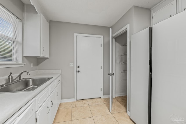 kitchen featuring dishwasher, white cabinetry, sink, light tile patterned floors, and a textured ceiling