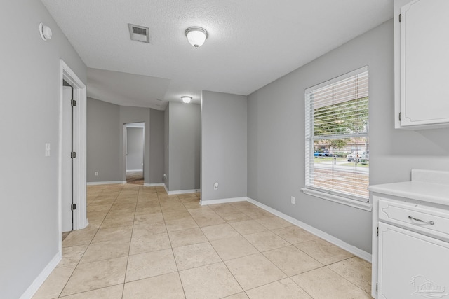 tiled empty room with a textured ceiling