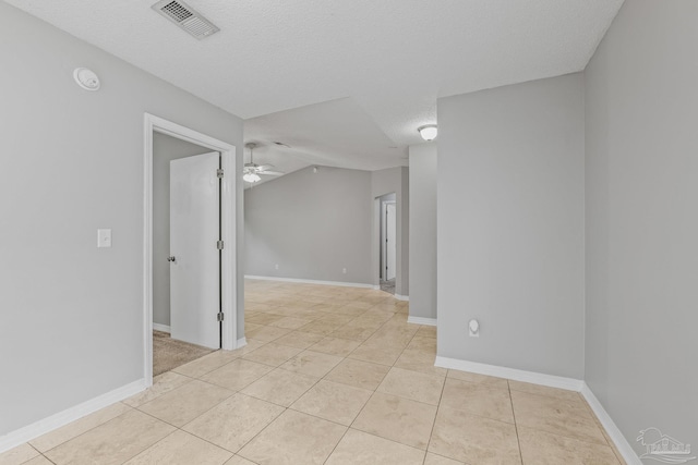 spare room with lofted ceiling, a textured ceiling, ceiling fan, and light tile patterned flooring