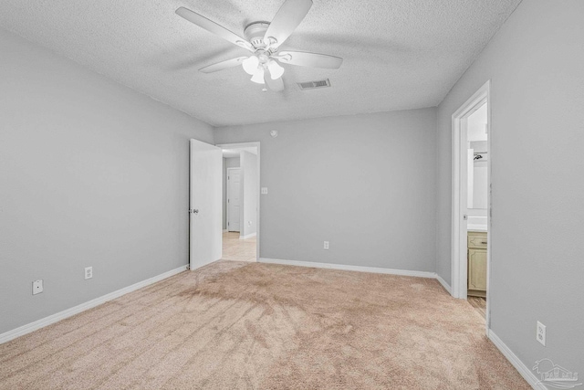 unfurnished bedroom with ceiling fan, light colored carpet, connected bathroom, and a textured ceiling