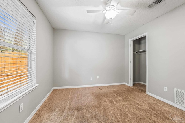 unfurnished bedroom with ceiling fan, a closet, carpet, and multiple windows