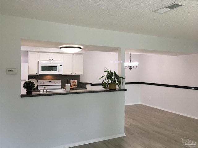 3385 Olive Rd Unit 2-D, Pensacola, FL 32514 - kitchen with white appliances, dark countertops, white cabinets, dark wood-style floors, and a peninsula