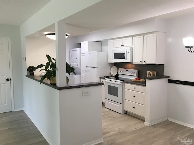 3385 Olive Rd Unit 2-D, Pensacola, FL 32514 - kitchen with white appliances, stacked washer / dryer, dark countertops, light wood-style flooring, and a peninsula