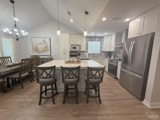 1450 N 11th Ave, Pensacola, FL 32503 - kitchen with appliances with stainless steel finishes, a chandelier, a center island, decorative backsplash, and white cabinets