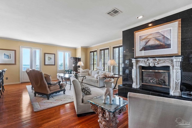 living room featuring a tile fireplace, crown molding, and hardwood / wood-style flooring