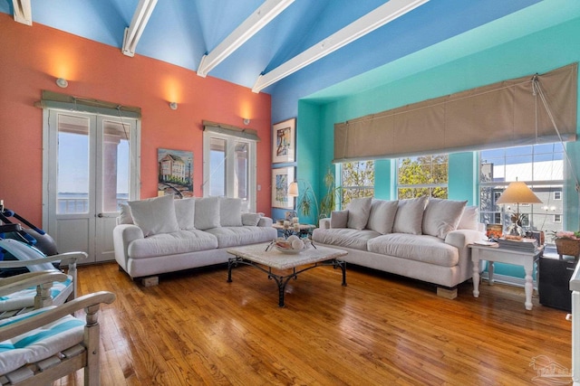 living room with wood-type flooring, high vaulted ceiling, and french doors