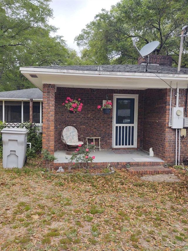 rear view of house featuring covered porch and brick siding