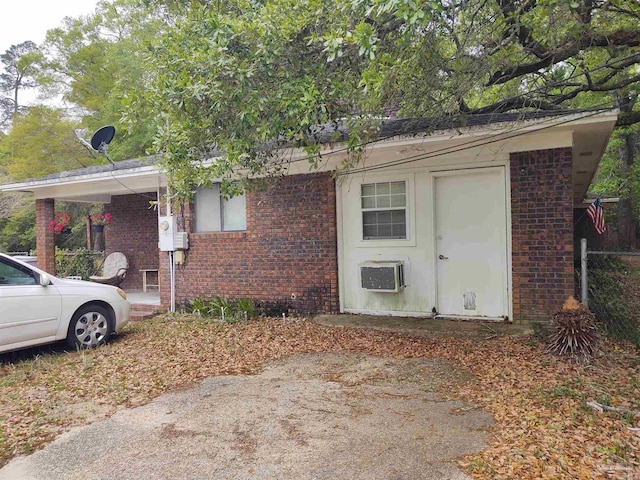 exterior space with brick siding and a wall mounted AC