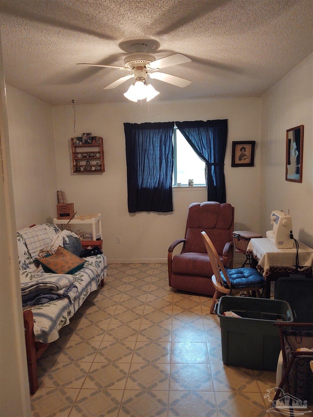 living room with baseboards, a ceiling fan, and a textured ceiling
