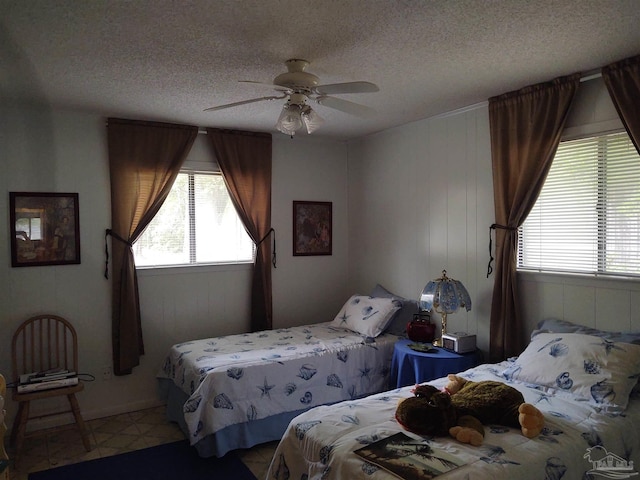 bedroom featuring ceiling fan, multiple windows, and a textured ceiling