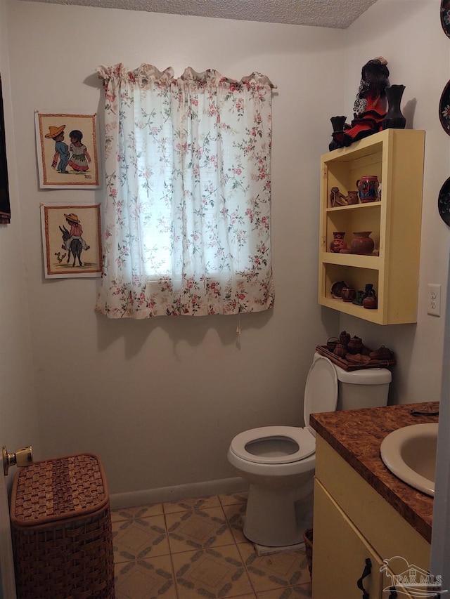 half bathroom featuring vanity, baseboards, and toilet