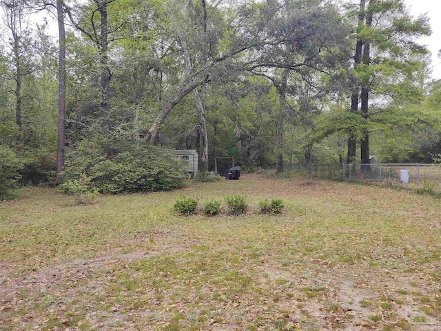 view of yard featuring a wooded view and fence