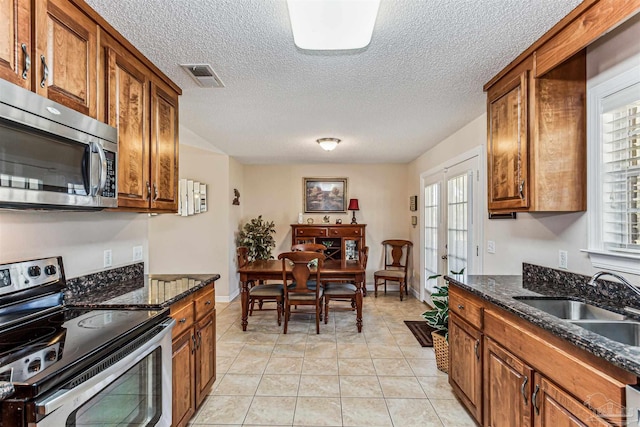 kitchen with a sink, stainless steel appliances, brown cabinets, and visible vents