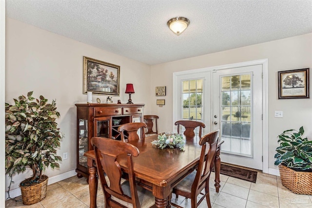 dining room featuring light tile patterned flooring, baseboards, and a textured ceiling