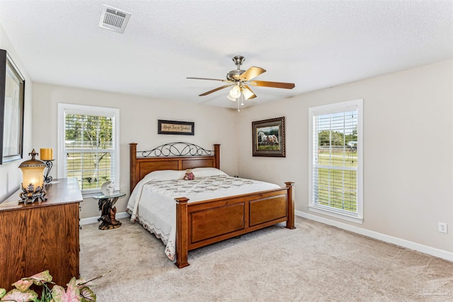 bedroom featuring visible vents, light colored carpet, and multiple windows