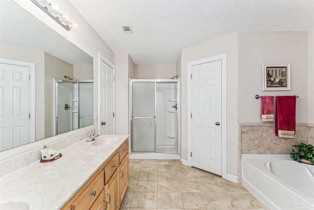 full bath featuring visible vents, a sink, a textured ceiling, a shower stall, and double vanity