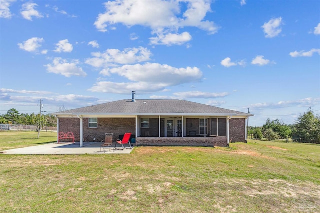 back of property featuring a yard, roof with shingles, a sunroom, brick siding, and a patio area