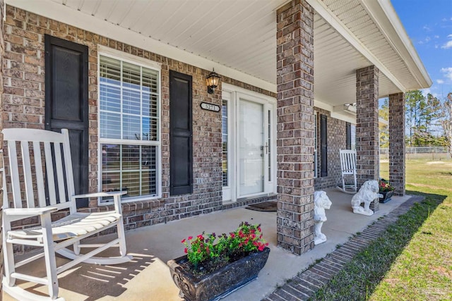 view of exterior entry with a porch and brick siding