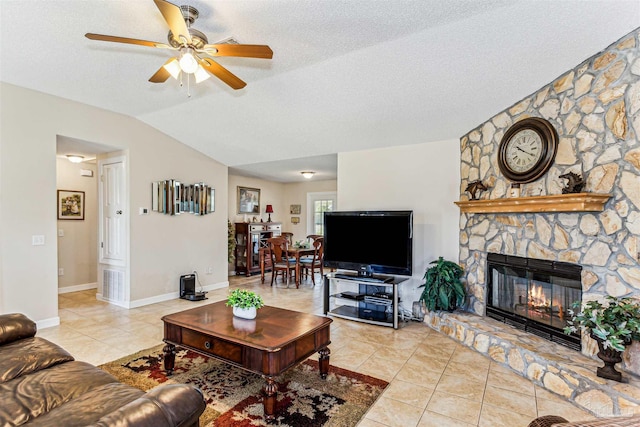 living room with a stone fireplace, ceiling fan, light tile patterned flooring, and vaulted ceiling