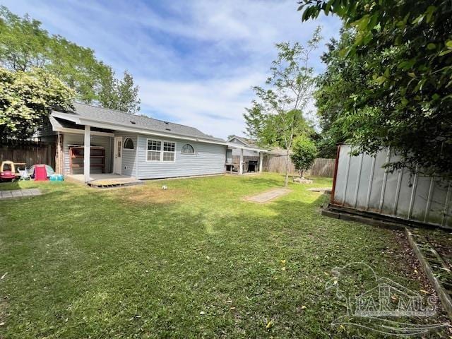 rear view of house with a fenced backyard, an outbuilding, a storage shed, and a lawn