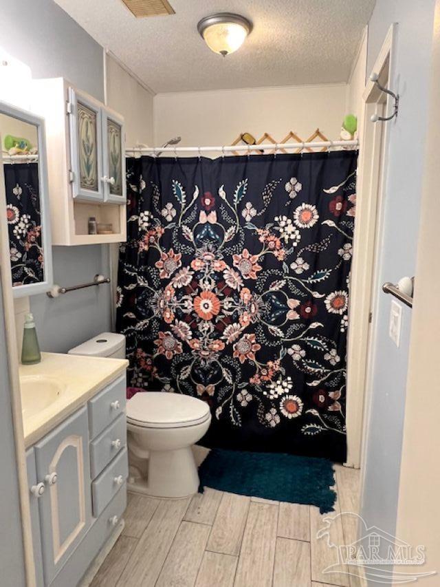 full bath with wood finished floors, a textured ceiling, vanity, a shower with curtain, and toilet