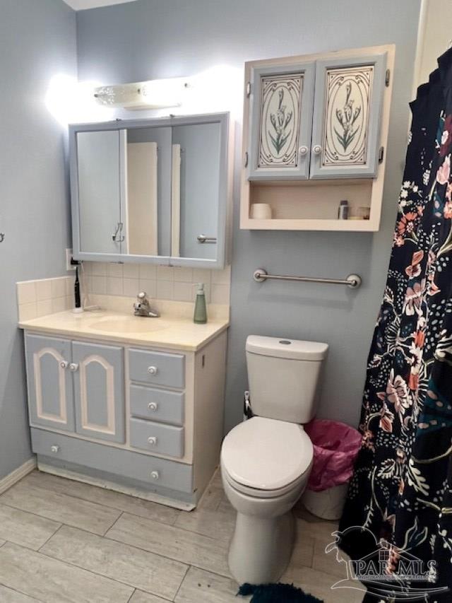 full bath with a shower with shower curtain, toilet, vanity, and decorative backsplash