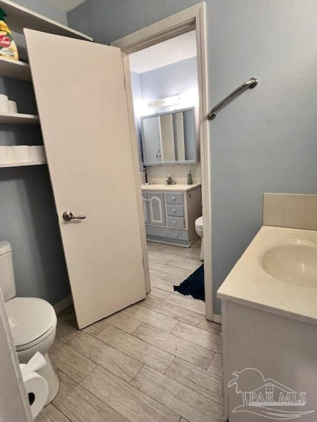 bathroom featuring vanity, wood finish floors, and toilet