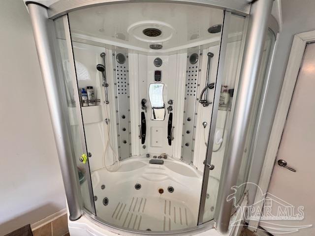 bathroom featuring a shower stall and a tub with jets