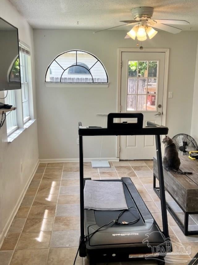 workout room featuring plenty of natural light, a textured ceiling, baseboards, and ceiling fan