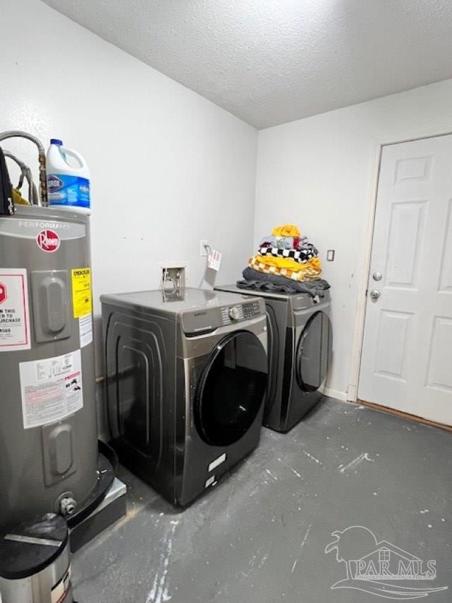 washroom with a textured ceiling, water heater, washer and clothes dryer, and laundry area