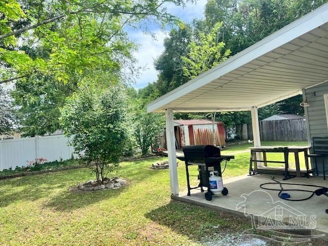 view of yard with a fenced backyard, an outbuilding, a patio area, and a shed