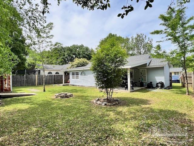 back of house featuring a fire pit, fence, a yard, and a patio