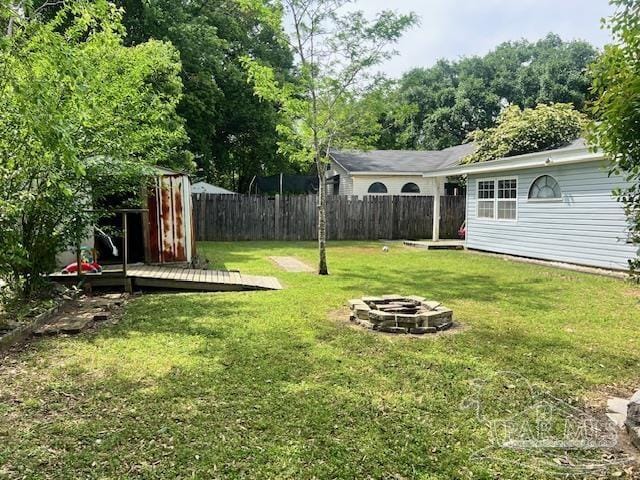 view of yard featuring a fire pit, a deck, and a fenced backyard