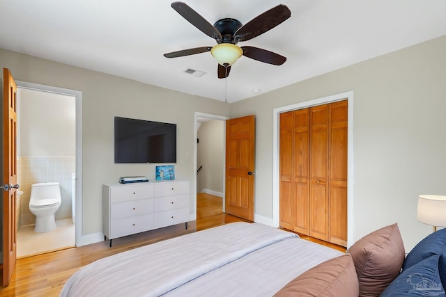 bedroom featuring a closet, light wood finished floors, ensuite bathroom, visible vents, and ceiling fan