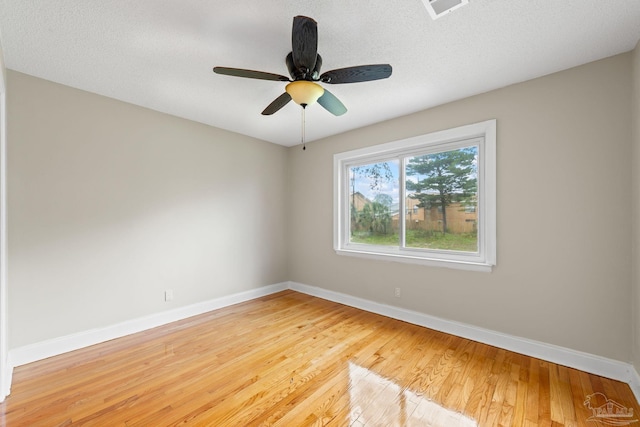 spare room with baseboards, a textured ceiling, visible vents, and light wood finished floors