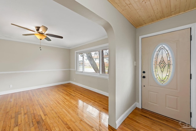 entrance foyer with baseboards, arched walkways, crown molding, and light wood-style floors