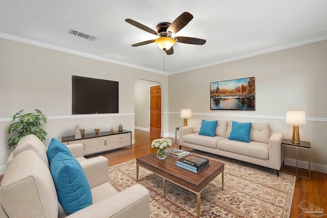 living area featuring visible vents, ornamental molding, wood finished floors, a ceiling fan, and arched walkways