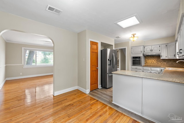 kitchen featuring a sink, appliances with stainless steel finishes, a peninsula, visible vents, and arched walkways