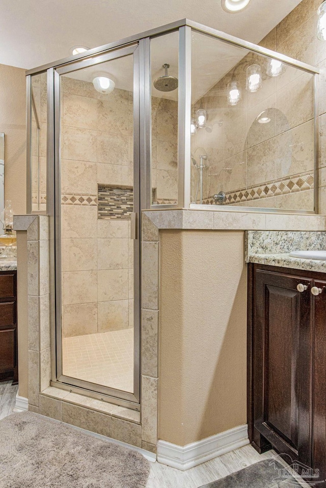 bathroom with a shower with door and vanity