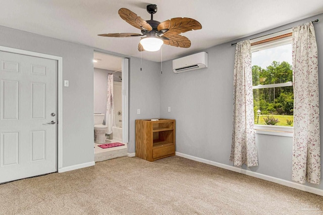 unfurnished bedroom featuring ceiling fan, ensuite bath, a wall mounted AC, and light carpet