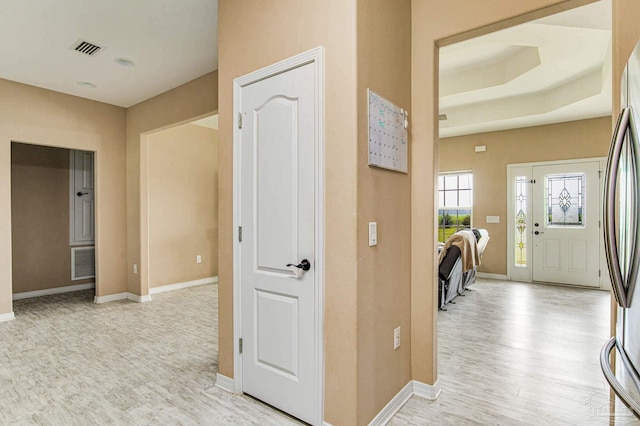 hallway featuring a raised ceiling and light hardwood / wood-style floors