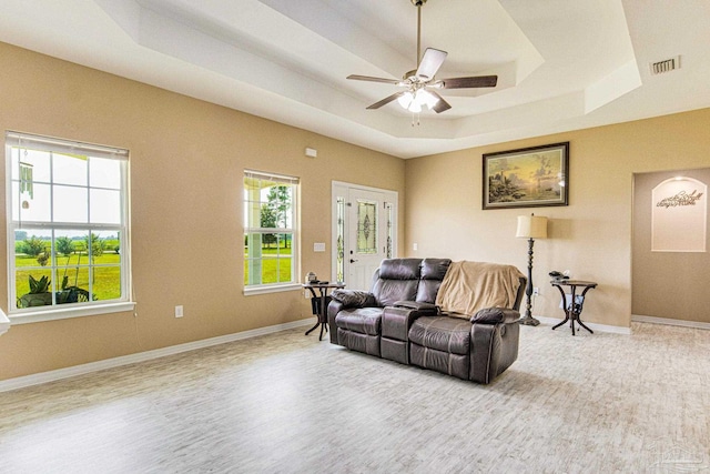 living room featuring ceiling fan, wood-type flooring, and a tray ceiling